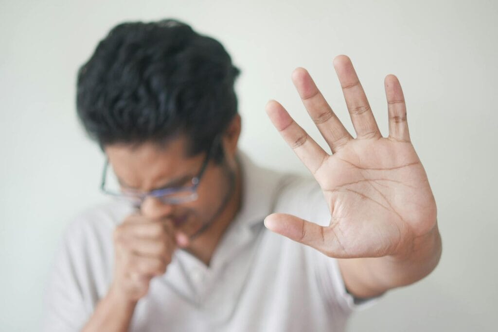 Unwell man covering cough with hand, showing sign of illness